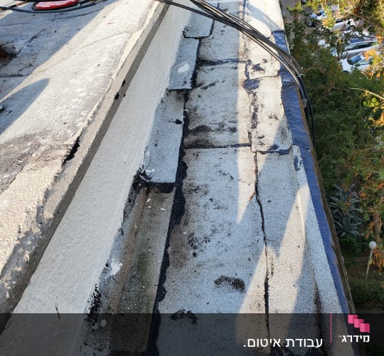גג עם חומרי איטום שחורים ולבנים, כבלים מונחים.